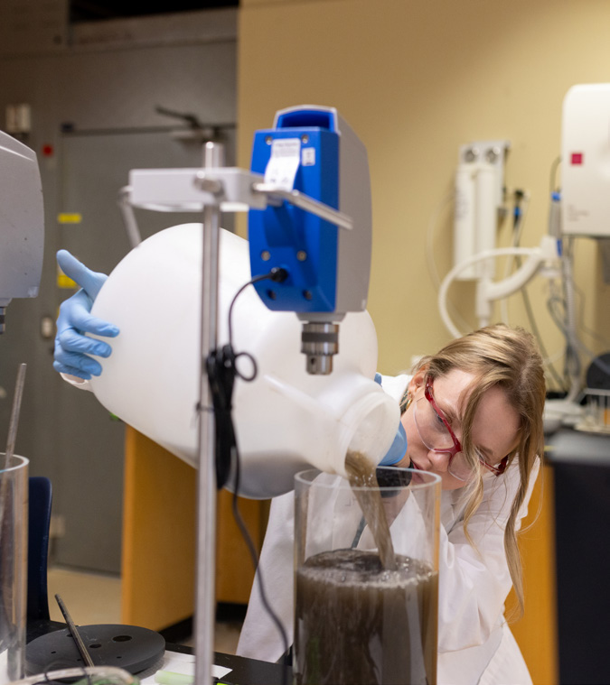 A student pouring brown liquid into a jar