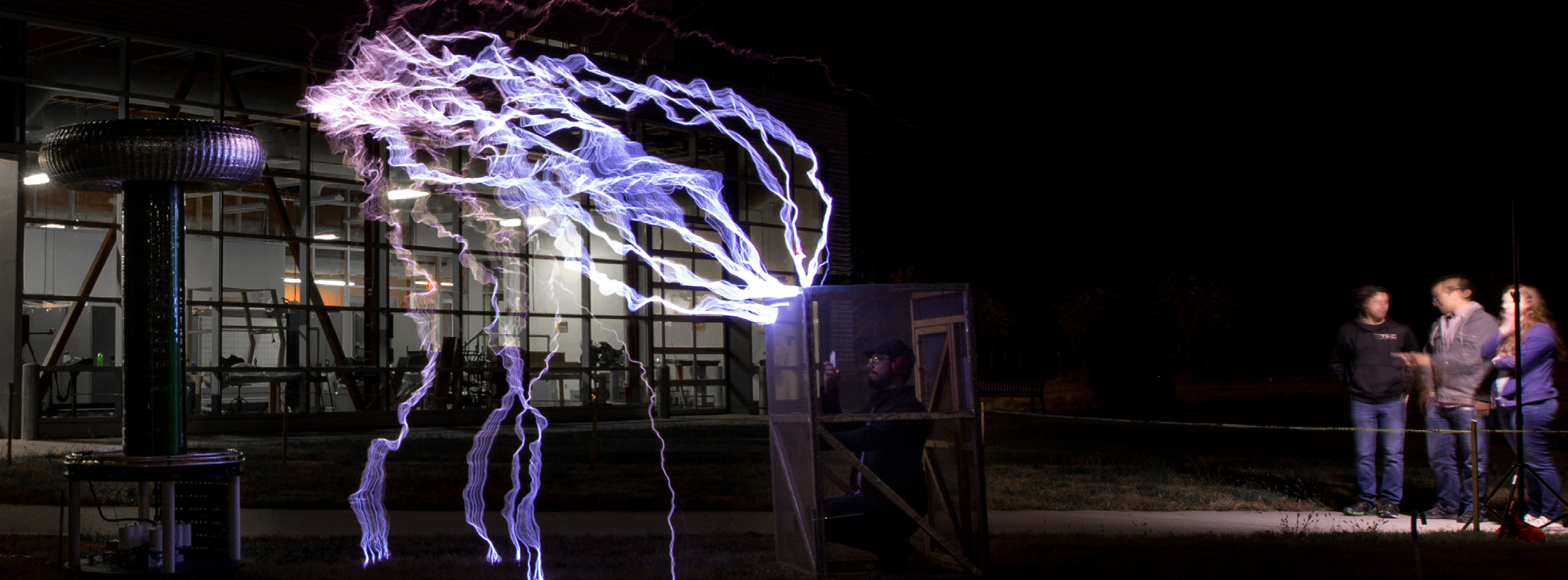 People observing a large tesla coil at night